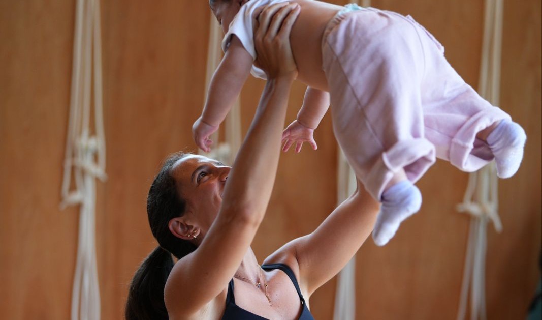 A mother lifting her baby overhead in the studio at Sola